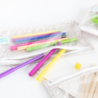 Close-up of Bumkins Clear Travel Bag 3-Pack: Wander on a white background, filled with colorful markers and art supplies.