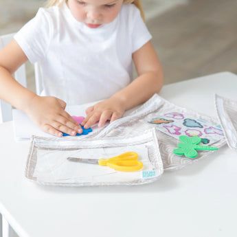 A child crafts with clay, stickers, and scissors in Bumkins Clear Travel Bag 3-Pack: Wander at a white table.