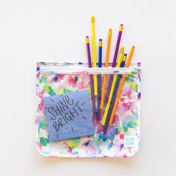 A vibrant TSA-compliant bag from Bumkins Clear Travel Bag 3-Pack features a Shine Bright! blue note on white.
