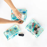 Packing TSA-approved items and a scrunchie into Bumkins Ocean Life Clear Travel Bag set, perfect for organizing essentials.
