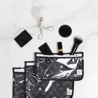 Bumkins Clear Travel Bag 3-Pack in Mickey Mouse design keeps makeup essentials organized and TSA-compliant on a marble surface.
